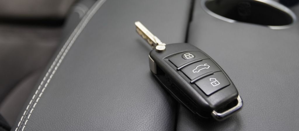 car key to a German luxury car the key is lying on dark leather.